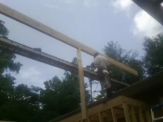 Carpenter setting a ridge beam over a new addition frame — Ice Dam Removal by Roofing Brothers in Minden City