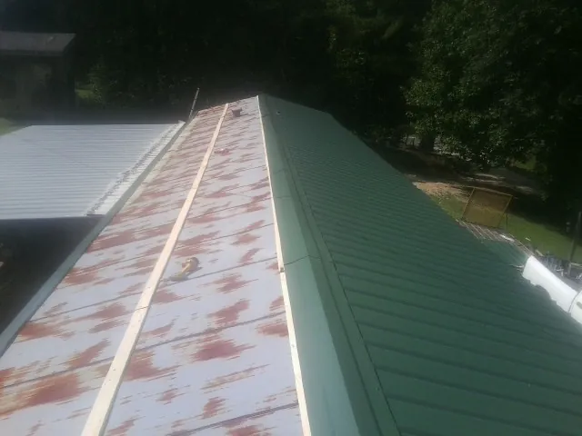 Old rusted panels beside newly installed green metal roofing — Wind Damage Roof Repair by Roofing Brothers in Minden City