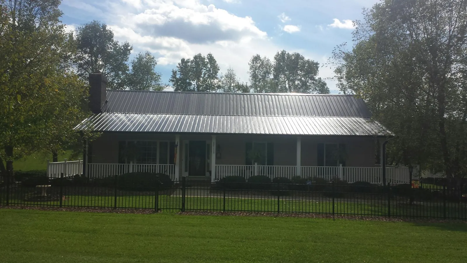 Gray metal roof on a brick ranch with a full width front porch — Gutter Guard Installation work by our crew in Minden City
