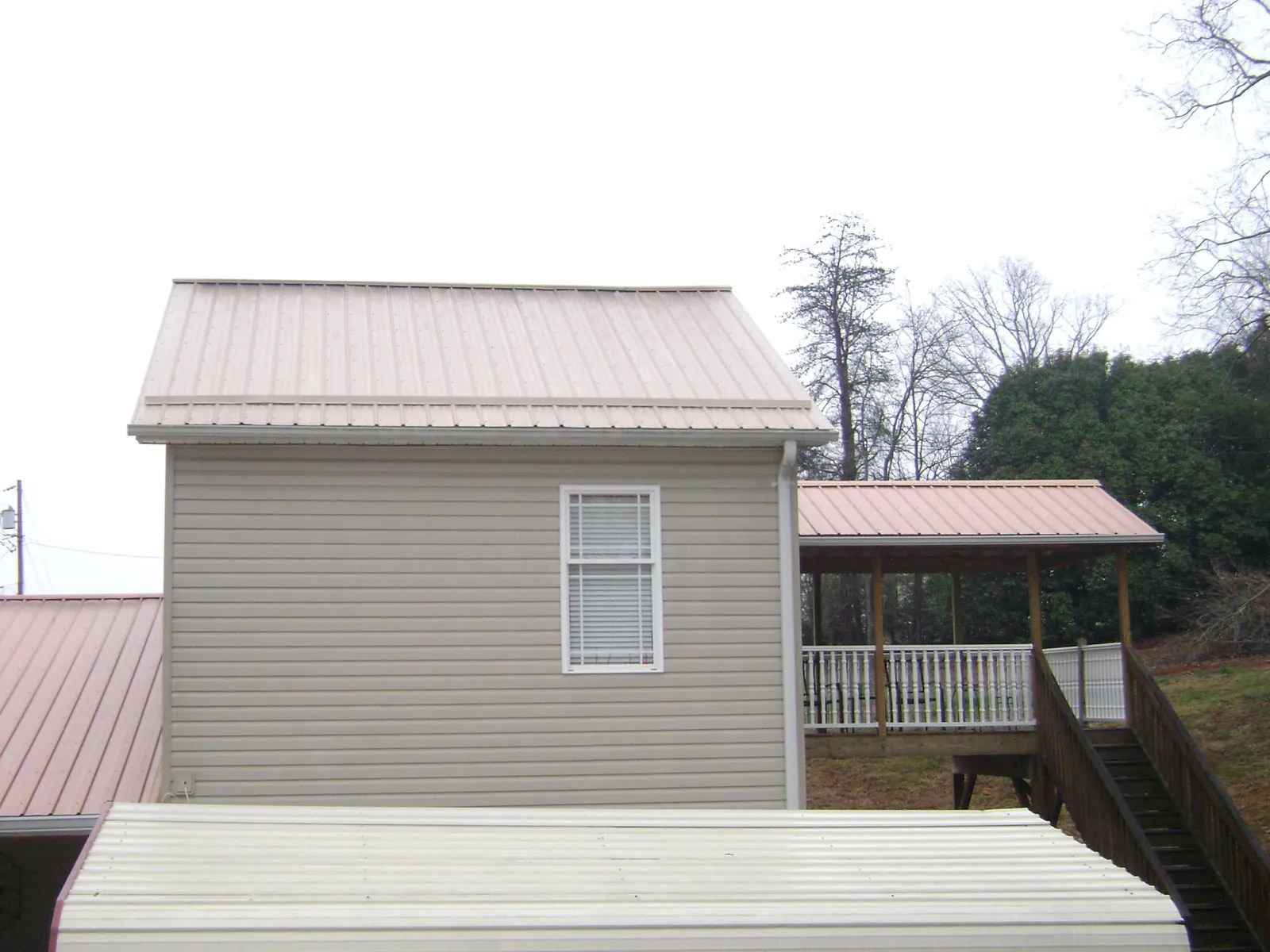 Tan metal roofs on a two story addition and attached porch, from a Roof Replacement job in Minden City