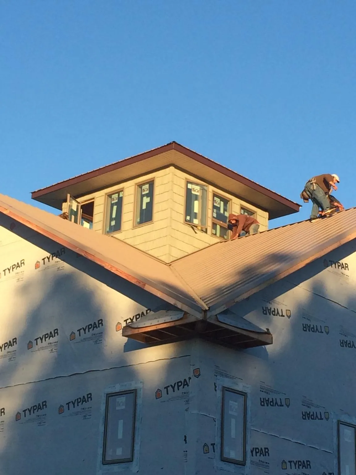 Roofers working around a rooftop cupola on a new metal roof at sunset — Roof Waterproofing in Minden City by Roofing Brothers